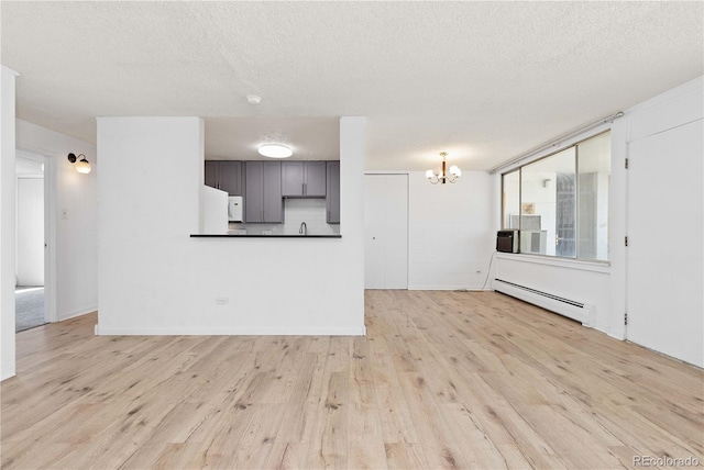 10185 W 25th Ave Unit 33, Lakewood, CO 80215 - unfurnished living room featuring baseboard heating, wood finished floors, a chandelier, a textured ceiling, and a sink