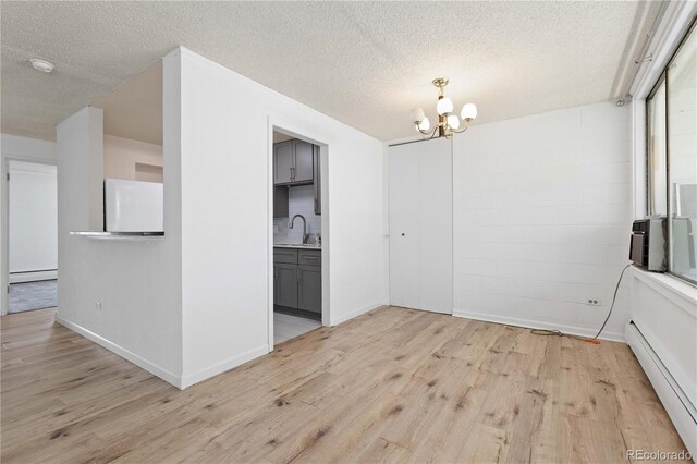 10185 W 25th Ave Unit 33, Lakewood, CO 80215 - unfurnished dining area with a baseboard radiator, light wood finished floors, a chandelier, and a textured ceiling