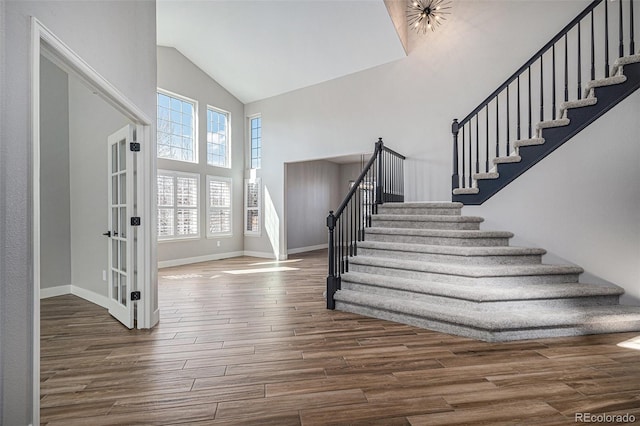 entrance foyer featuring high vaulted ceiling, stairs, and wood finished floors