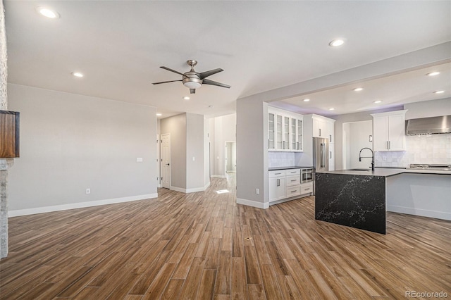 kitchen with wood finished floors, a ceiling fan, open floor plan, and a sink