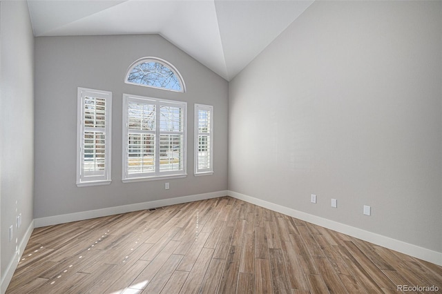 unfurnished room with lofted ceiling, wood finished floors, and baseboards