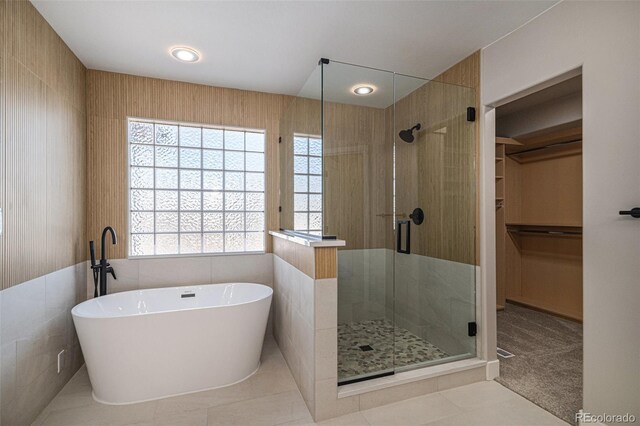 bathroom featuring plenty of natural light, a soaking tub, a stall shower, and a spacious closet