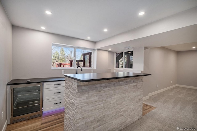 bar with beverage cooler, recessed lighting, a bar, and baseboards