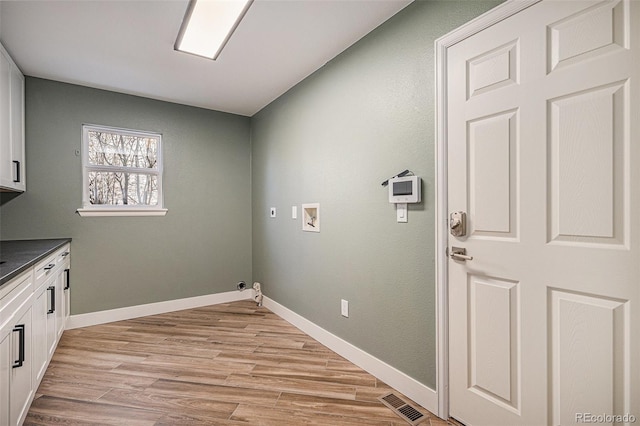 washroom with visible vents, washer hookup, light wood-style flooring, cabinet space, and baseboards