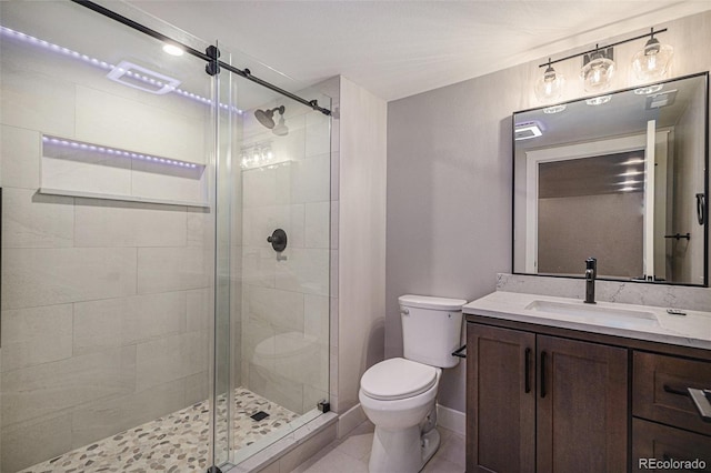 bathroom with a stall shower, toilet, vanity, and baseboards