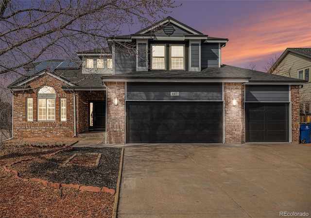 traditional-style home with brick siding, an attached garage, and concrete driveway