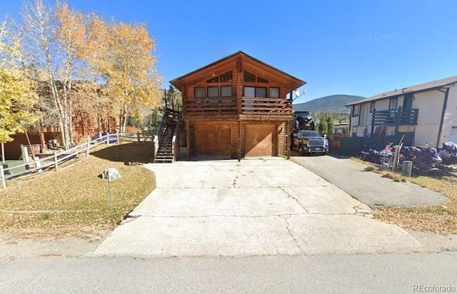 view of front facade with stairs, driveway, fence, and a mountain view