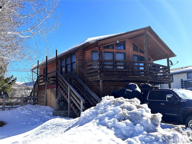 snow covered property featuring a garage and stairway