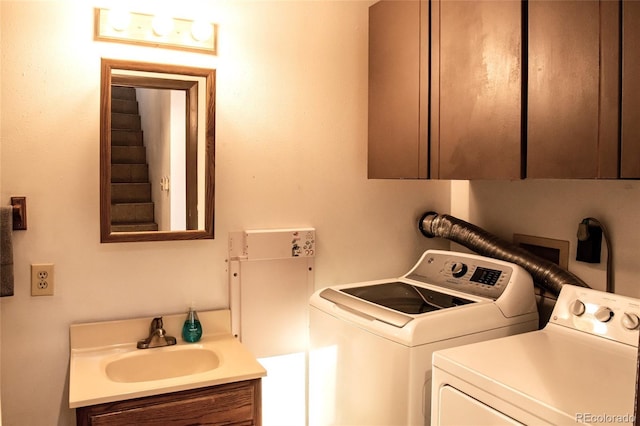 clothes washing area with independent washer and dryer, cabinet space, and a sink