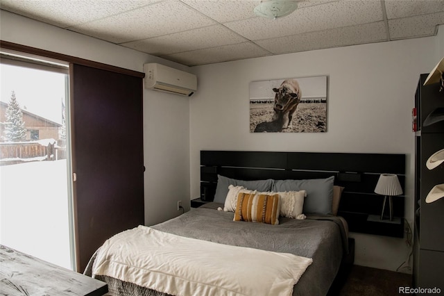 bedroom featuring a paneled ceiling and a wall mounted AC