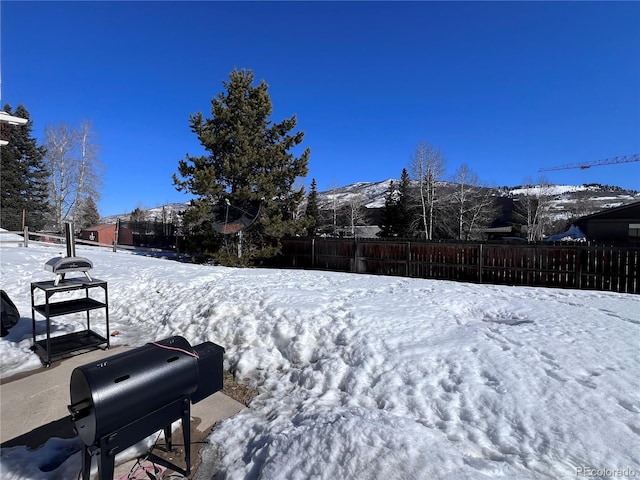 yard layered in snow with fence and a mountain view