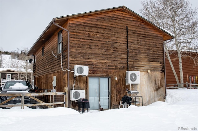 snow covered back of property featuring ac unit