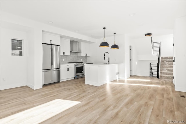 kitchen with a sink, white cabinets, wall chimney exhaust hood, stainless steel appliances, and tasteful backsplash