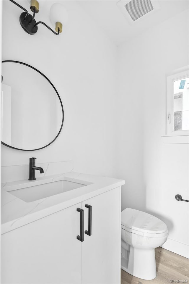 bathroom with vanity, toilet, visible vents, and wood finished floors