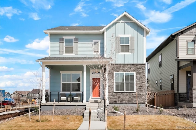 21209 E 62nd Ave, Aurora, CO 80019 - view of front of property featuring board and batten siding, a porch, stone siding, fence, and roof with shingles