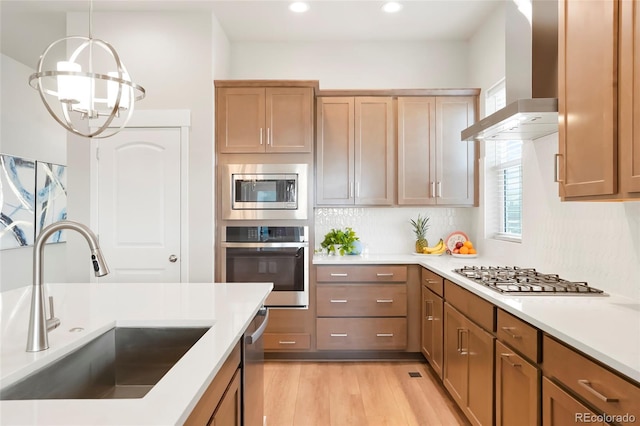 21209 E 62nd Ave, Aurora, CO 80019 - kitchen featuring stainless steel appliances, a sink, wall chimney exhaust hood, light wood-style floors, and a chandelier