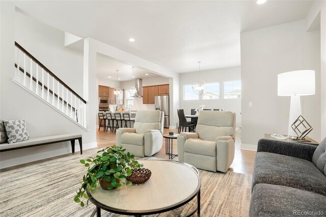 21209 E 62nd Ave, Aurora, CO 80019 - living room with light wood-style flooring, recessed lighting, a chandelier, and stairway