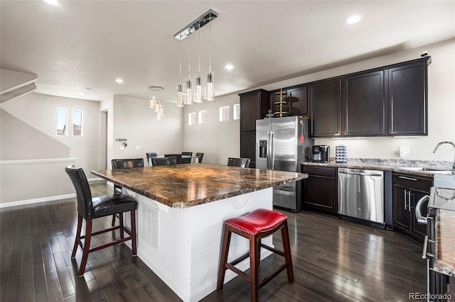 18651 E 53rd Ave, Denver, CO 80249 - kitchen with stainless steel appliances, a kitchen bar, a sink, a center island, and dark wood-type flooring