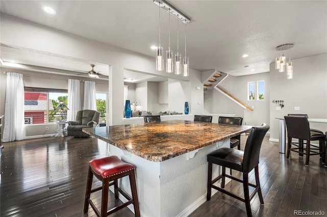 18651 E 53rd Ave, Denver, CO 80249 - kitchen with baseboards, dark wood-type flooring, dark countertops, a breakfast bar area, and recessed lighting