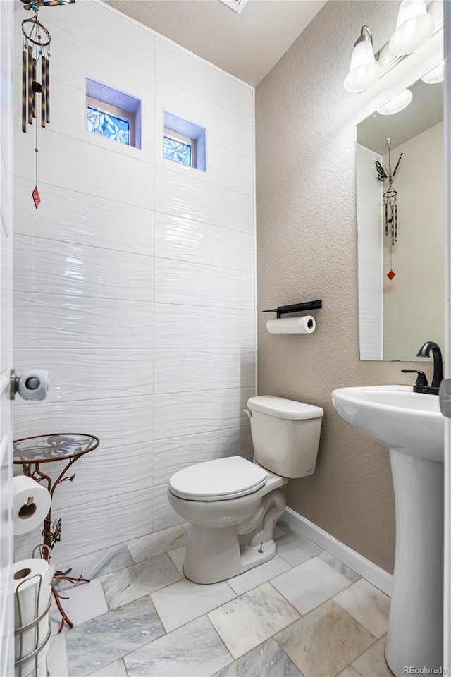 18651 E 53rd Ave, Denver, CO 80249 - bathroom with toilet, a textured wall, baseboards, and a sink