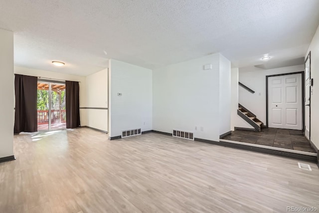 3320 Simmelink Loop, Colorado Springs, CO 80916 - unfurnished living room featuring baseboards, a textured ceiling, stairway, and wood finished floors