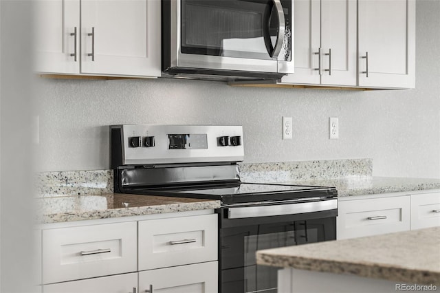 kitchen with light stone countertops, white cabinetry, and stainless steel appliances