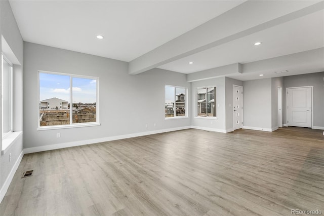 unfurnished living room with beamed ceiling and light hardwood / wood-style flooring