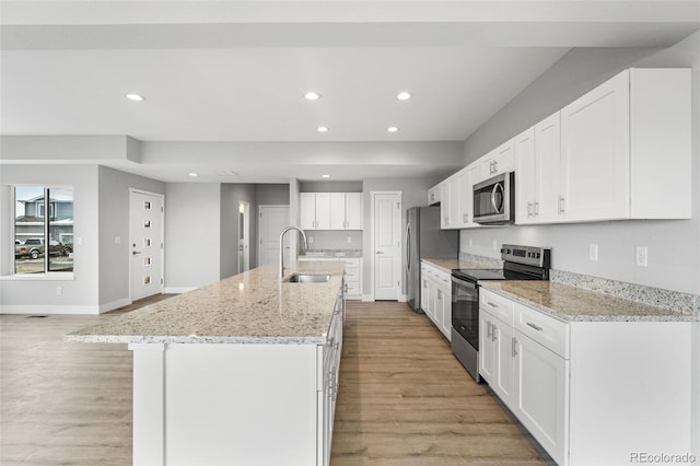 kitchen featuring white cabinets, a center island with sink, sink, appliances with stainless steel finishes, and light hardwood / wood-style floors