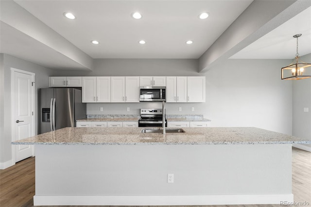 kitchen featuring appliances with stainless steel finishes, a center island with sink, and white cabinetry