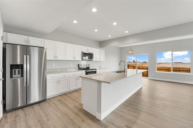 kitchen with light stone countertops, stainless steel appliances, white cabinetry, and sink