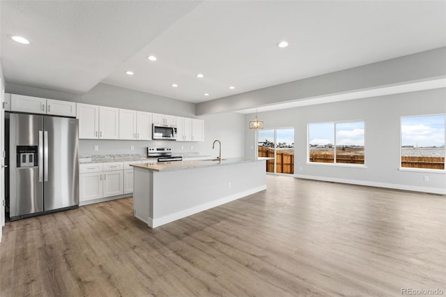 kitchen with a kitchen island with sink, sink, light hardwood / wood-style flooring, appliances with stainless steel finishes, and white cabinetry