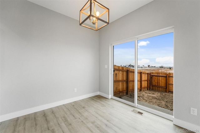 unfurnished room featuring light hardwood / wood-style flooring and an inviting chandelier