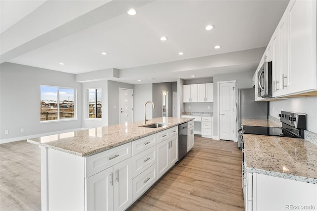 kitchen with light wood-type flooring, stainless steel appliances, sink, a center island with sink, and white cabinetry