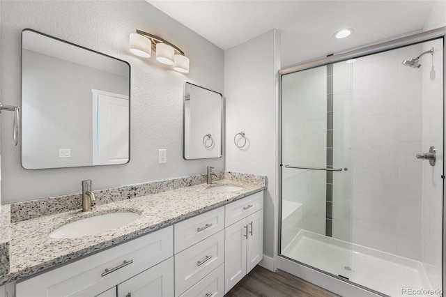 bathroom with a shower with shower door, wood-type flooring, and vanity