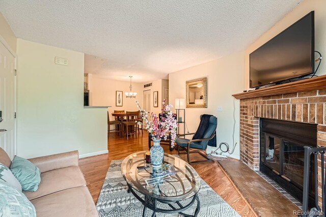 7881 Allison Way Unit 303, Arvada, CO 80005 - living area featuring a chandelier, wood finished floors, a brick fireplace, and a textured ceiling