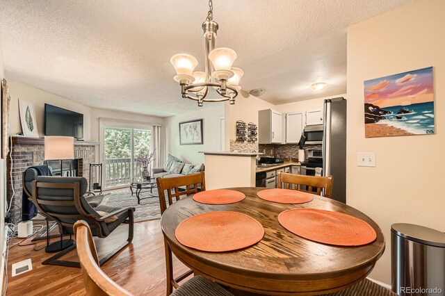 7881 Allison Way Unit 303, Arvada, CO 80005 - dining room featuring a textured ceiling, light wood-style floors, a chandelier, and a fireplace
