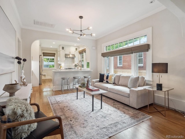 660 S Clarkson St, Denver, CO 80209 - living room with arched walkways, ornamental molding, light wood-type flooring, and a chandelier