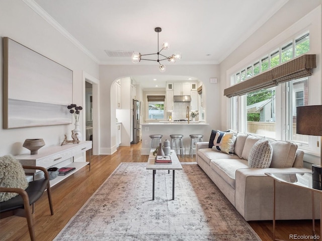 660 S Clarkson St, Denver, CO 80209 - living area with arched walkways, crown molding, light wood-style flooring, a chandelier, and baseboards