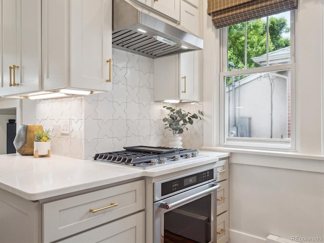 660 S Clarkson St, Denver, CO 80209 - kitchen with exhaust hood, stainless steel appliances, light countertops, white cabinetry, and backsplash