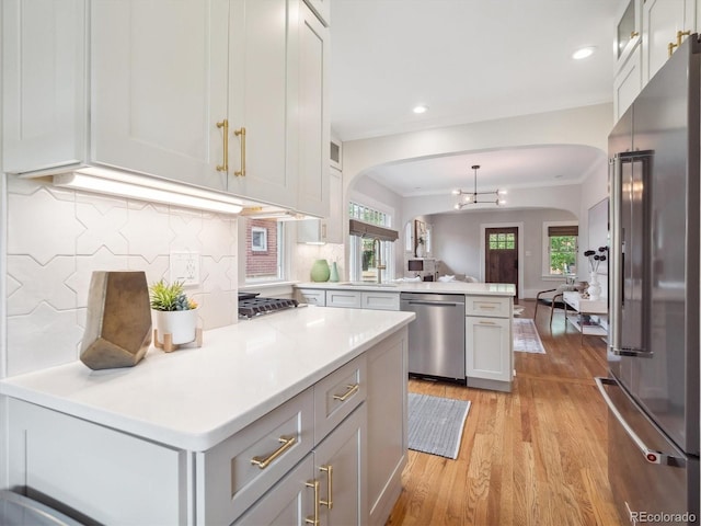 660 S Clarkson St, Denver, CO 80209 - kitchen with stainless steel appliances, arched walkways, a peninsula, light wood-style flooring, and light countertops