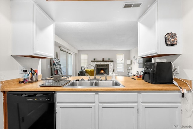16001 E Alaska Pl Unit 12, Aurora, CO 80017 - kitchen featuring black dishwasher, white cabinets, open floor plan, and a warm lit fireplace