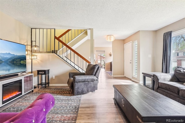 7925 W Layton Ave Unit 500, Littleton, CO 80123 - living room with wood finished floors, stairway, a textured ceiling, a glass covered fireplace, and baseboards