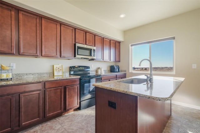 kitchen featuring light tile patterned floors, sink, light stone counters, a center island with sink, and black / electric stove