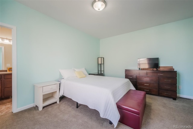 bedroom featuring connected bathroom and light carpet