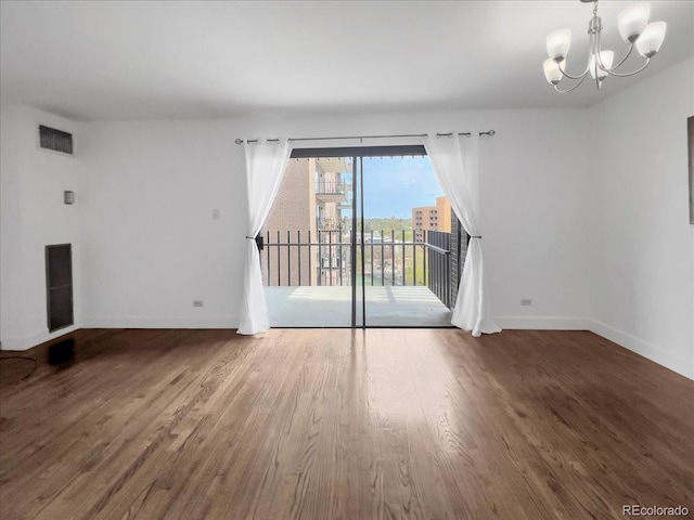 unfurnished living room featuring baseboards, a chandelier, and wood finished floors