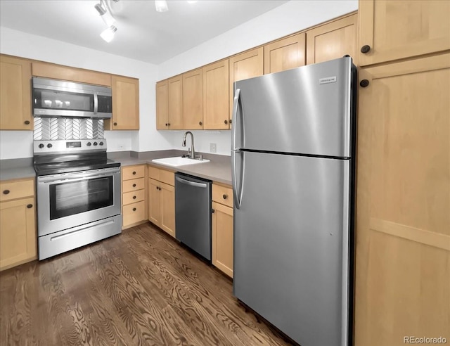 kitchen featuring stainless steel appliances, a sink, light brown cabinets, and dark wood finished floors