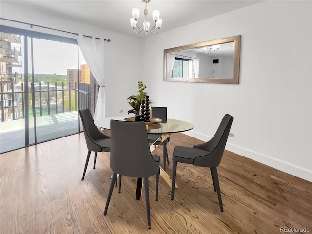 dining area featuring a chandelier, baseboards, and wood finished floors