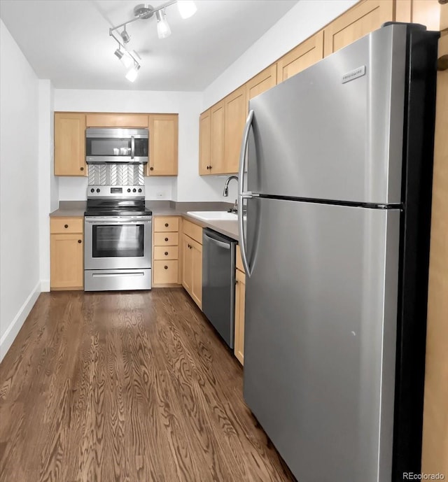 kitchen featuring stainless steel appliances, light brown cabinetry, a sink, dark wood-style floors, and baseboards