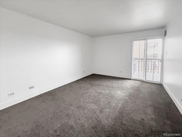 empty room featuring baseboards and dark carpet
