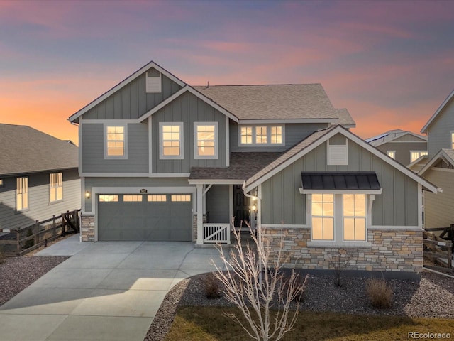 craftsman house featuring roof with shingles, an attached garage, concrete driveway, stone siding, and board and batten siding